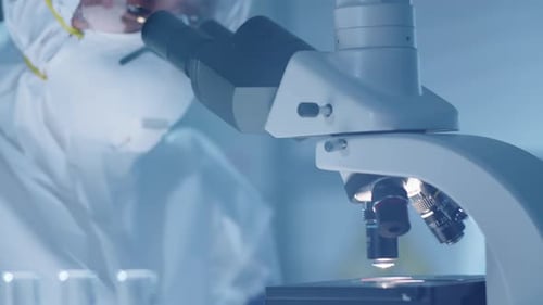 Scientist Examining Sample Through Microscope in Lab