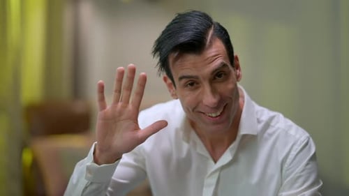 Man Smiling and Waving Hello Indoors