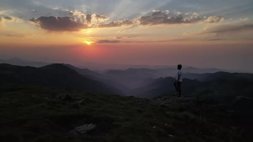 Homem observando a natureza ao pôr do sol