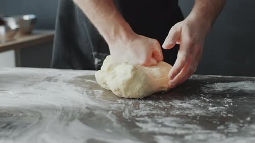 Baker Kneading Dough on Table