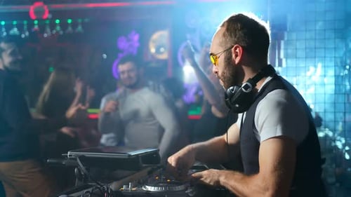 DJ Performing at a Nightclub with Dancing Crowd