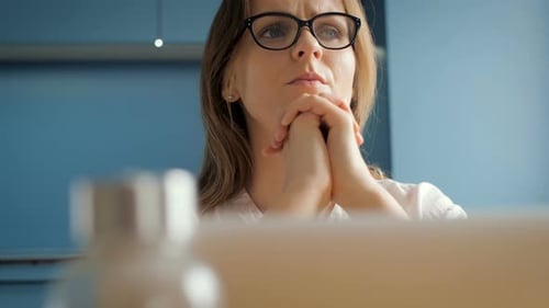 Woman Ponders at Laptop in Bright Home