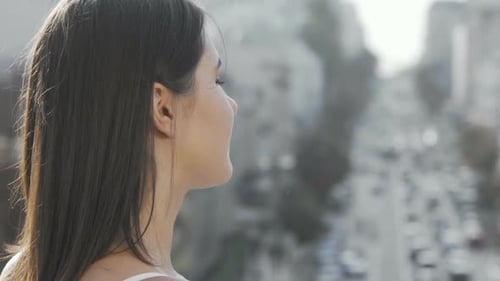 Young Woman Smiling To the Camera Over Her Shoulder While Observing Busy City