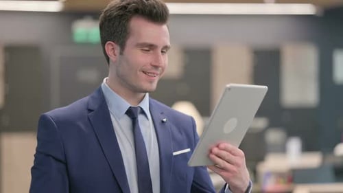 Portrait of Businessman Celebrating on Tablet in Office
