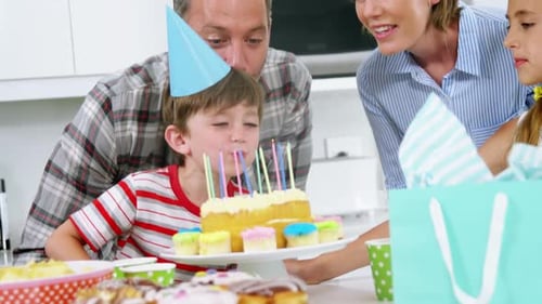Boy Blows Out Birthday Candles with Family