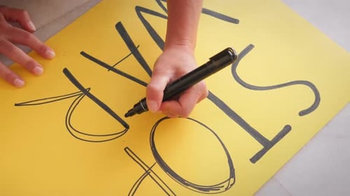 Hand Writes "Stop War" Message on Protest Poster