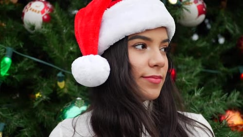 Smiling Woman Wearing Santa Hat by Christmas Tree