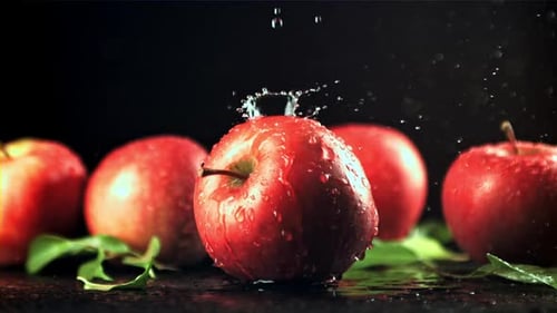 Wasser mit Spritzern fällt auf den roten Apfel