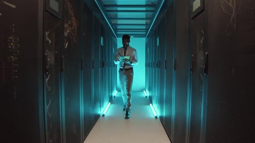 IT Specialist Walking along Row of Operational Server Racks