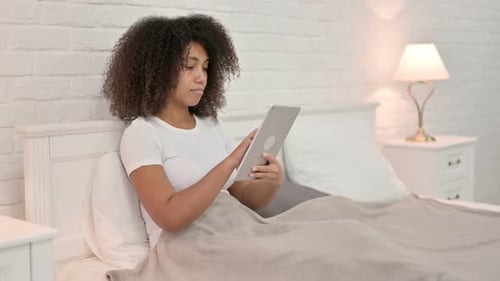 Woman Relaxes in Bed Using Tablet