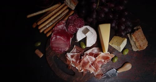 Antipasto with Grapes Slowly Rotates on a Cutting Board.