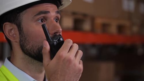 Trabajador de almacén barbudo hablando por walkietalkie
