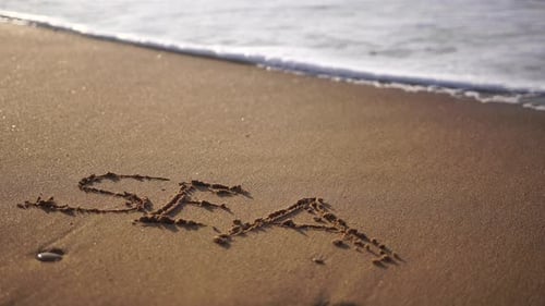 SEA Figures Hand Written in the Golden Sand on Beautiful Sunset Golden Light