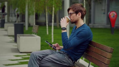 Young Adult Using Phone and Drinking Coffee
