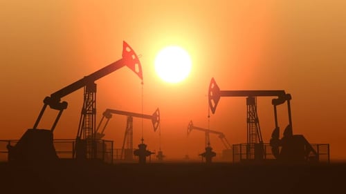 Working Oil Pump Jacks in a Desert Against Sunset Extracting Crude Oil