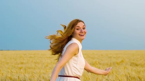 following shot of red haired woman running in wheat field in slow motion