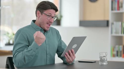 Man Celebrating Success Using Tablet at Home