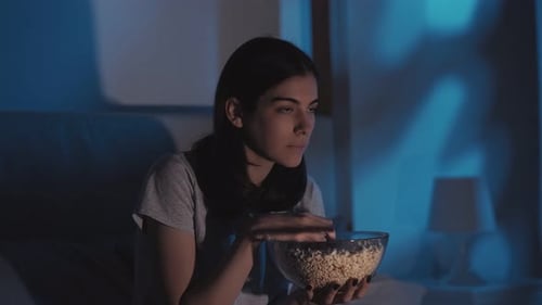 Woman Watches Scary Movie and Eats Popcorn