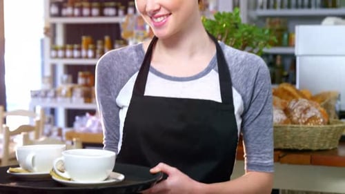 Kellnerin hält Kaffeetassen in einem Tablett