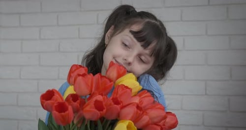 Smiling Child with Tulips Bouquet Against Brick Wall