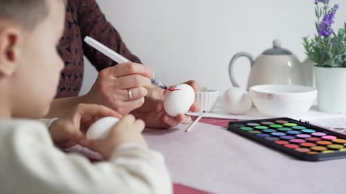 Happy Easter. Mom teaches her son how to paint Easter eggs