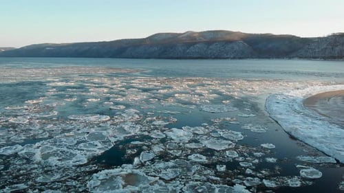 Aerial View. Footage of the Freezing River, in the Given Bare Mountains Covered with Snow