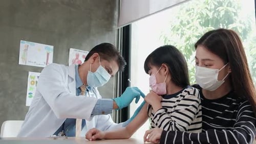 Male doctor vaccinating Asian girl At the pediatrics clinic.