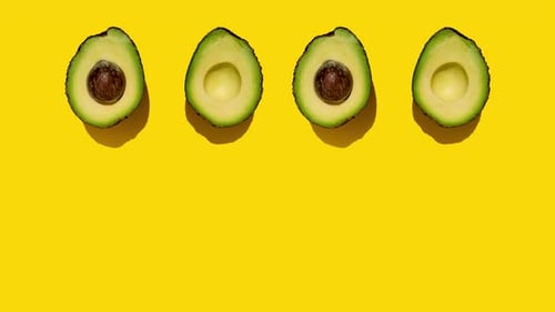 Reihe halbierter Avocados auf gelbem Hintergrund