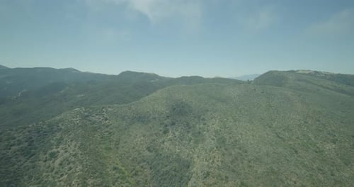 Helicopter aerial shot of green mountain with one lonely road, cloudy day