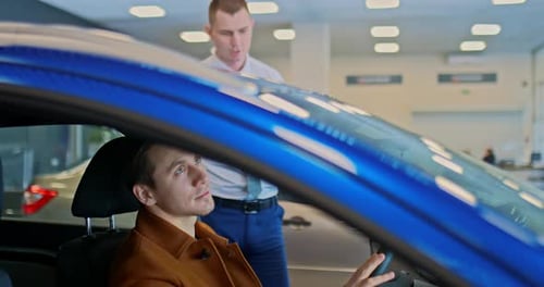 Man in Car Talking to Salesman at Dealership
