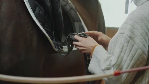 Femme attachant des sangles de selle à cheval