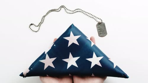 Hands with Folded Flag and Military Dog Tag