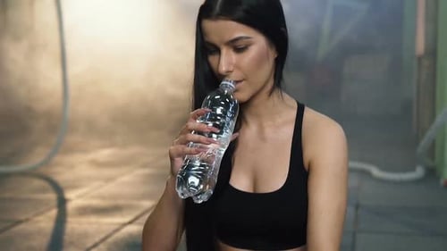 Attractive Fit Woman Drinking Water After Training in the Gym
