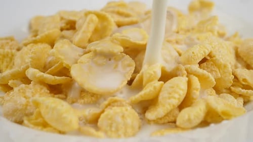 Milk Pouring onto Crispy Corn Flakes in Bowl