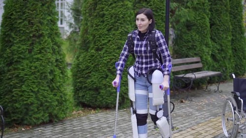 Young Disabled Woman Uses Exoskeleton To Walk in Park