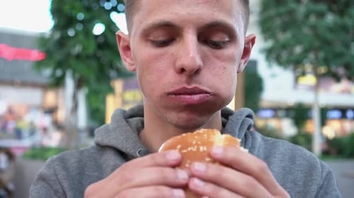 Close Up Shot of a Handsome Caucasian Male Eating a Burger in a Fast Food Restaurant