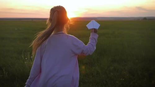 Child Runs with Paper Airplane at Sunset