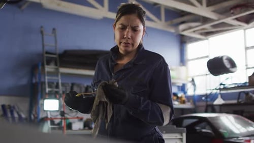 Female mechanic cleaning equipment of the car with a cloth at a car service station