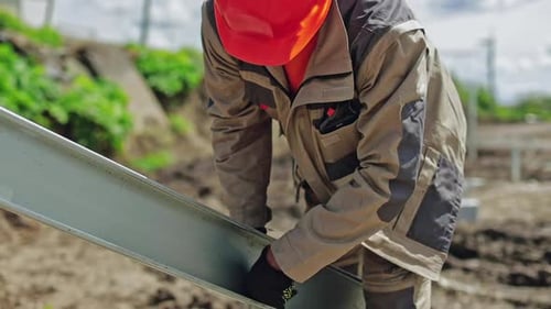 Construction Worker Securing a Metal Beam at Site