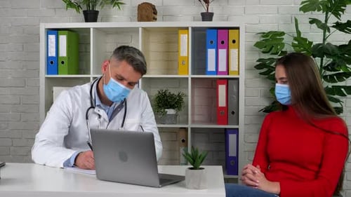 Doctor and patient wears protective masks on faces in hospital communicates