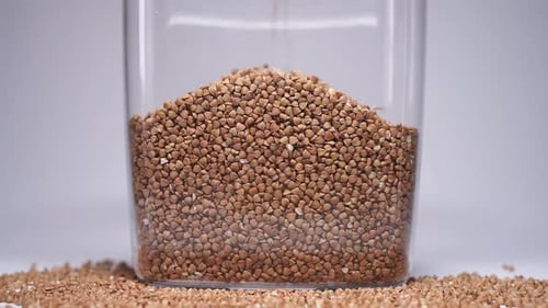 Buckwheat Grains Pouring into Clear Container
