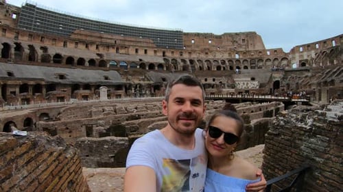 Couple taking selfie in Colosseum amphitheater in Rome, Italy