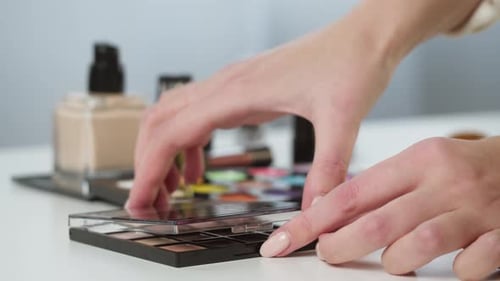 Hands Opening Eyeshadow Palette with Various Cosmetics