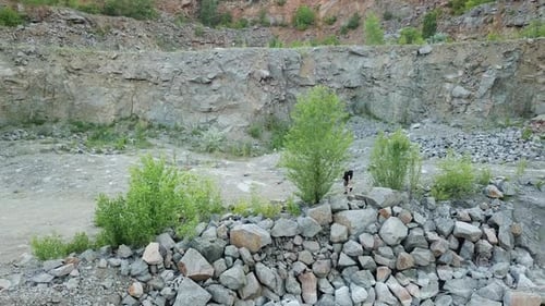 Tourist man with rucksack walking by stone trail over the precipice with mountain lake.