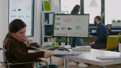 Woman in Wheelchair Works on Computer in Office