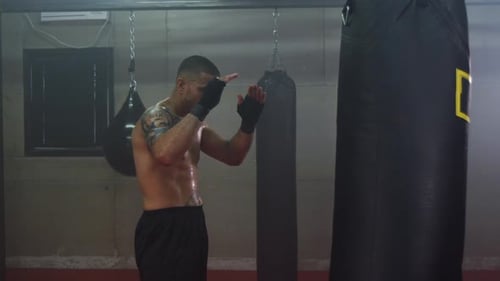 Muscular Man Practices Martial Arts With Punching Bag