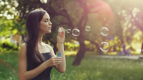 Woman Blowing Bubbles in a Sunny Park