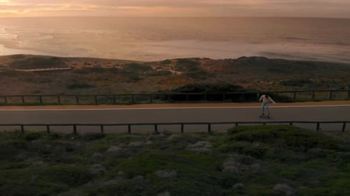 Man on Longboard Ride Empty Road at Sunset
