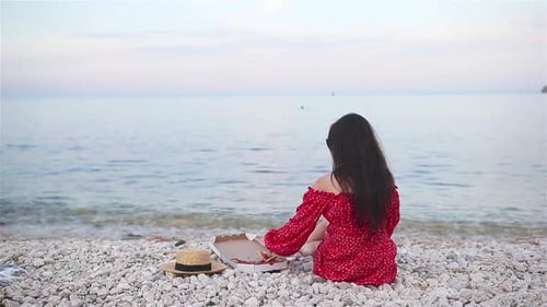Woman Having a Picnic with Pizza on the Beach