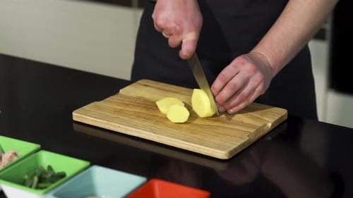 Person Slicing Potato on a Cutting Board
